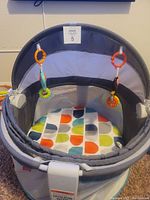 Front view of Fisher Price baby dome with colorful padded interior and hanging toys on canopy