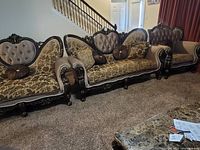 Three chairs side by side, front view showing carving, upholstery and pillows