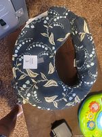 Top angle showing the U-shaped nursing pillow with floral slipcover, slight fading visible.