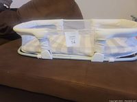 Side angle photo showing the padded mesh sides with beige check pattern and white padded edges over a metal support frame.