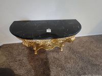Top view of Versailles console table showing the black marble top with soft white veining.