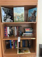 Bookshelf showing a variety of books including JFK Remembered and Book of Nursery and Mother Goose Rhymes grouped on shelves