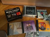 Michael Connelly CD collection box, several holiday-themed CDs including 'Holiday' and Johnny Mathis Christmas album, stacked on a wooden floor.