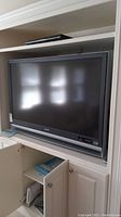 Front view of the Sony 50 inch Grand Wega TV in a built-in shelving space, showing the screen and lower speaker panel with logos.