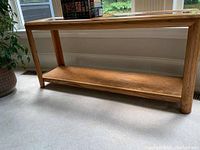 Full view of the wooden sofa table showing the bottom shelf and legs.