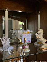 Photo showing white milk glass bon-bon dish with yellow rose decoration, two matching candle holders, porcelain horse figurine, and Exedco dinner bell.