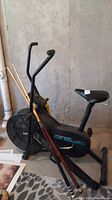 Side and front view of Vitamaster exercise bike with two pool cues resting against it.