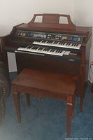 Side angle view of the electric organ with bench showing wooden construction and visible wear.