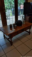 Front view of Broyhill wood coffee table with items placed on top showing its overall structure and drawer front.