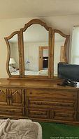 Front view of wooden dresser with dovetail drawers and double doors with mirror above that includes three panels