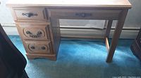 Photo of small wooden desk with visible drawer fronts and worn top surface.