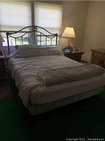 Full bed assembled with metal frame and headboard, mattress and bedding included for staging only.