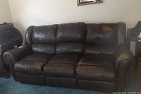 Front view of the full brown leather 3-seat sofa showing cushions and visible wear on seating surfaces.