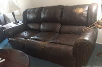 Brown leather 3-seat sofa in room setting, visible wear and aging on cushions and backrest.