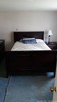 Front view of the wooden sleigh bed with headboard, mattress optional, light bedding shown but not included