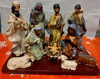 Complete 12 piece ceramic nativity set displayed on a wooden base, showing all human figures and animals.