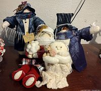 Photo of the four plush snowman figurines grouped together on a wooden surface showcasing their size and variety.
