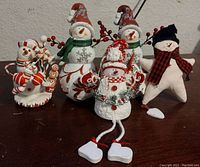 Front view of all five snowman decorations arranged side by side on a surface.