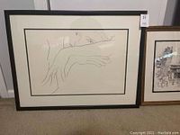 Black and white abstract line art in a large black and white framed print, showing a partial face and arm.