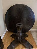 Round dark wood tabletop with MaxSold lot sticker, showing plank design and dark finish.