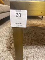 Close-up photo of a brass table leg showing wear marks and auction sticker.