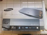 Photo of Samsung BD-D6700 Blu-ray Smart DVD Player box showing front side with product image and basic features.
