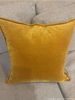 Front view of the gold velvet sofa pillow on a beige couch