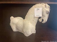 Front and side views of the ceramic Trojan Horse statue, showing its textured surface, facial details, and overall shape.