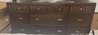 Front view of the large wooden dresser showing all 9 drawers and metal hardware.