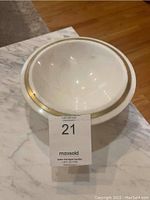 Side view of round marble bowl showing smooth white marble with brass rim inlay.