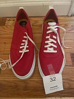 Front top view of both red Cole Haan sneakers with white laces, showing the upper design and size tag.
