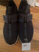 Top view showing the strap band and mesh upper of the black Nike slip on sneaker with TRAINING text on strap.