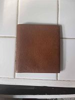 Closed brown calfskin leather wallet showing natural leather texture.