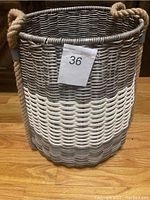 Side view of the wicker basket showing the woven two-tone gray and white pattern with attached rope handles.