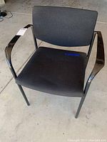 Front view of a black chair showing cushioned seat and back with metal armrests and legs.