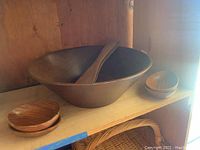 Large wooden bowl with wooden ladle and two small wooden bowls on shelf