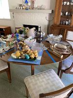 Round wooden dining table with leaf inserts shown with various decorative items on top.