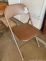 Side view of one brown padded metal folding chair.