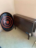 Photo of the wooden folding table next to the decorative platter leaning against the wall.