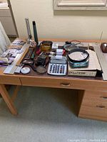 Various office supplies including magnifiers, calculator, binocular magnifier, tapes and flashlights on wooden desk