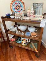 Full view of vintage wooden rolling cart with various items placed on the shelves (contents not included in sale).