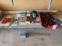 Photo of various tools and hardware laid out on a surface including staple tool, screwdrivers, different hammers, nails and screws in boxes, and small hand tools.