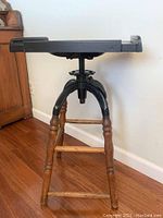 Side profile of the vintage adjustable table displaying the metal top with raised edges and wooden legs.
