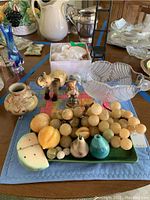 Overview of vintage decor items including glassware, figurines, marble fruit and ceramic vase on table