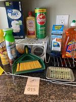 Photo showing cleaning products including trash bags, Brasso polish, Comet bleach, ceramic cooktop cleaner kit, Ajax dish soap, Swiffer duster spray, dustpan with brush, and soap dish.