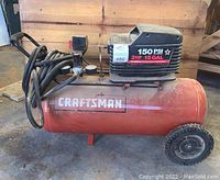 Side view of the Craftsman air compressor showing the red tank with Craftsman logo and black motor housing with specification label.