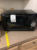Front angled view of black Magic Chef microwave oven showing the door with window and control panel with buttons and keypad.