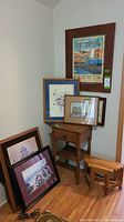 Photo showing maple side table, small oak stool, and six pieces of framed artwork arranged around them.