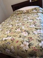 Full queen size bed with floral bedding on wooden headboard frame with storage drawers.