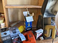 View of group with drill bit sharpener box, rotary pier cutter yellow handle, BernzOmatic torch tank, spool of metal wire and abrasive open mesh box.
